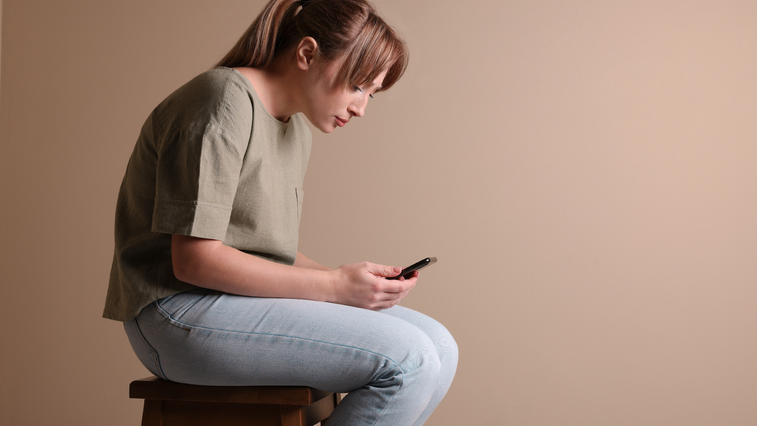 Woman Looking Down At Phone With A Forward Head Posture Hump